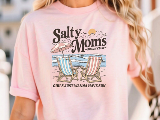 a woman wearing a pink shirt that says salty moms beach club