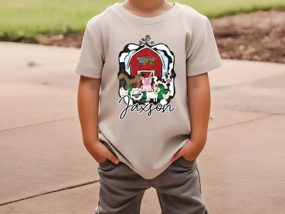 a young boy wearing a gray shirt with a barn on it