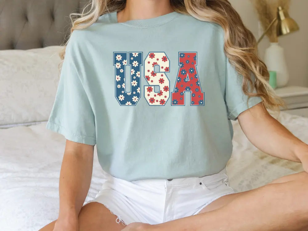 a woman sitting on a bed wearing a usa t - shirt