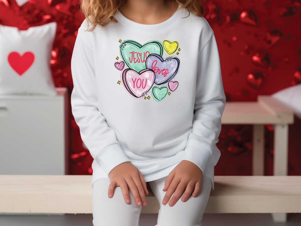 a little girl sitting on a bench wearing a sweatshirt with hearts on it