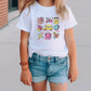 a little girl wearing a white shirt and denim shorts