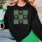 a woman sitting on a couch wearing a black sweater with shamrocks on it