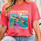 A woman wearing a red t-shirt with a colorful graphic of a turtle swimming in the ocean.