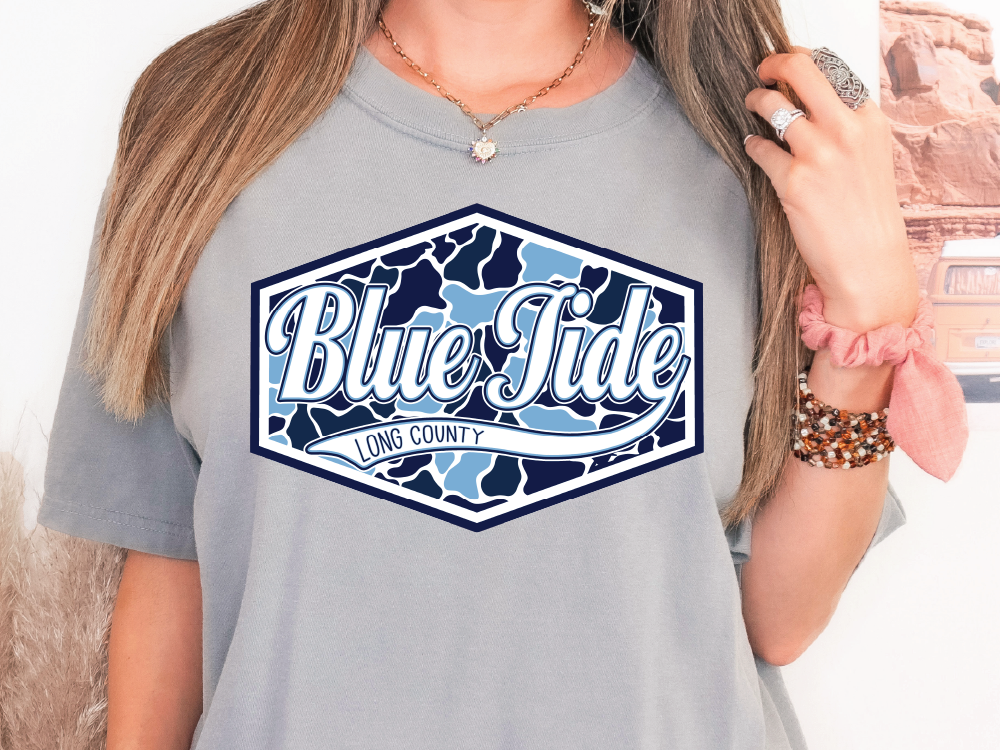 A woman wearing a gray t-shirt with a graphic design that says "Blue Tide Long County".