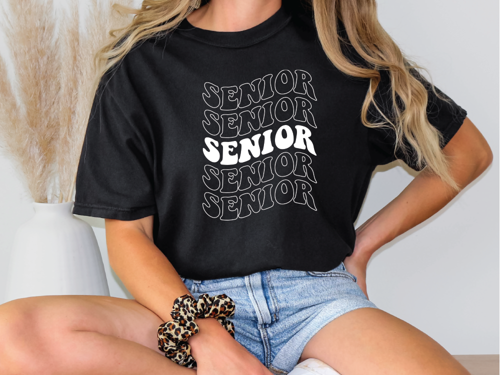 a woman sitting on a table wearing a black shirt with the words senior senior senior