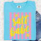 A blue t-shirt with a yellow and pink striped design and the text "salt babe" printed on it, along with a pair of denim shorts.