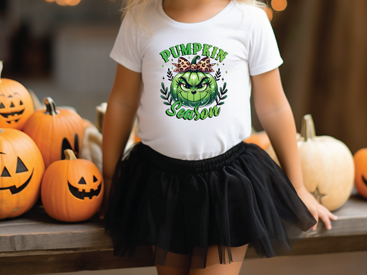 a little girl wearing a pumpkin shirt and a tutu skirt