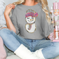 a woman sitting on a bed with a snowman t - shirt on