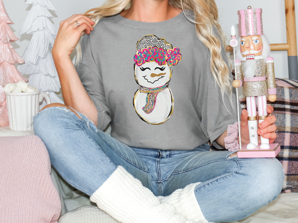 a woman sitting on a bed with a snowman t - shirt on