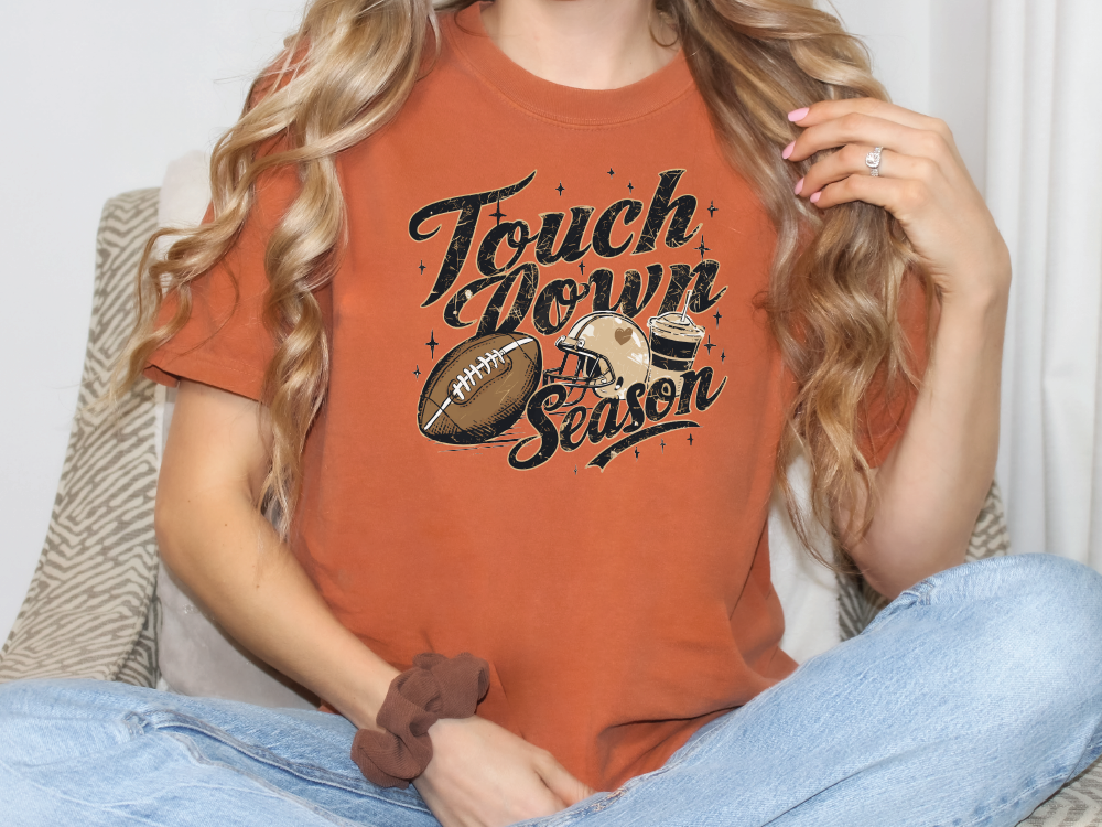 a woman sitting on a couch wearing a t - shirt with a football on it