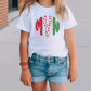 a little girl standing on a sidewalk wearing a white shirt with candy canes on