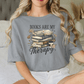 A woman wearing a gray t-shirt with a graphic design of books and flowers, along with the text "Books are my therapy".