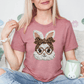 A woman wearing a pink t-shirt with a bunny design and glasses is sitting on a couch, holding a mug.
