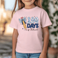 A young girl wearing a pink t-shirt with a graphic design that says "100 DAYS of School" and features a pencil and a bow.