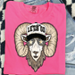 A pink t-shirt with a graphic design of a ram wearing sunglasses and a hat with the text "LET'S GO" printed on it.