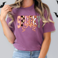 A woman wearing a purple t-shirt with the word "SPOOKY" printed on it, standing in front of a wall with bats.