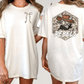 two different views of a white t-shirt with a graphic design on the back. The design features a cartoon cowboy character wearing a hat and the word "REBELS" written below the character.