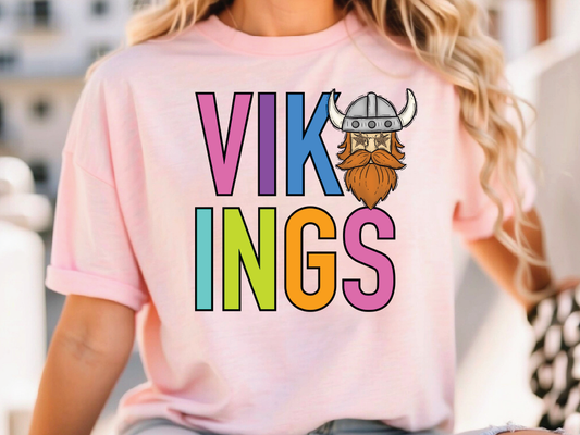 A person wearing a pink t-shirt with the text "VIKINGS" and a cartoon Viking helmet printed on it.