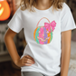 a little girl wearing a white t - shirt with a basket on it