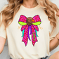 A woman wearing a white t-shirt with a colorful graphic design of a bird, specifically a hawk, wearing a pink bow.
