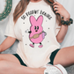 a woman sitting on the ground wearing a pink bunny t - shirt