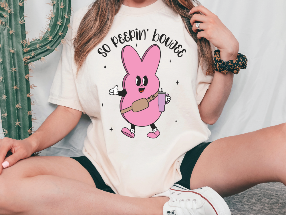 a woman sitting on the ground wearing a pink bunny t - shirt