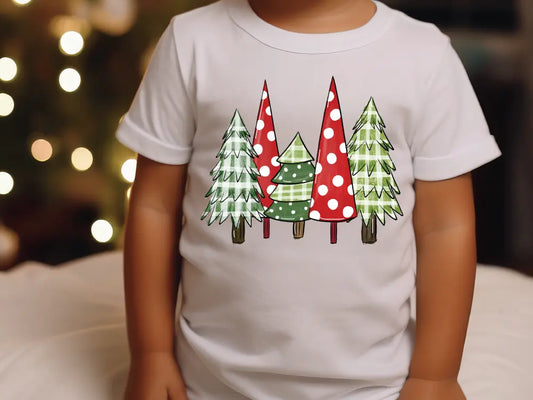 a small child wearing a white shirt with christmas trees on it