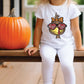 a little girl sitting on a porch next to a pumpkin