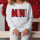 a young girl sitting on a bench wearing a white sweatshirt with the word mnn