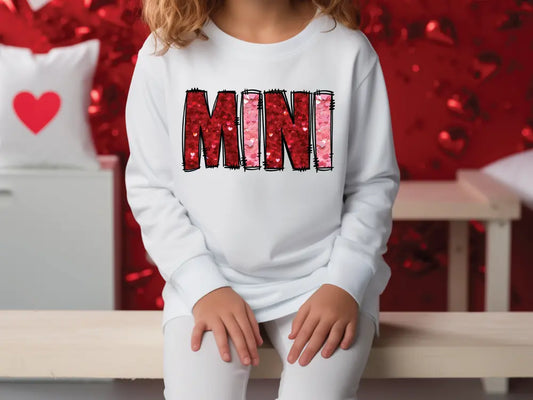 a young girl sitting on a bench wearing a white sweatshirt with the word mnn