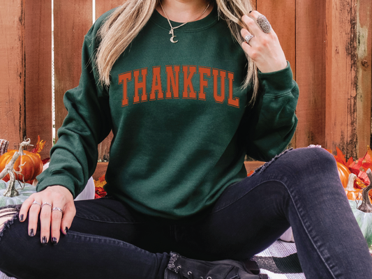 a woman sitting on the ground wearing a green sweatshirt