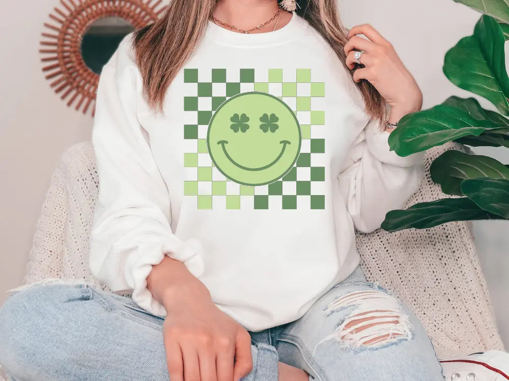 a woman sitting on a couch wearing a sweatshirt with a smiley face on it