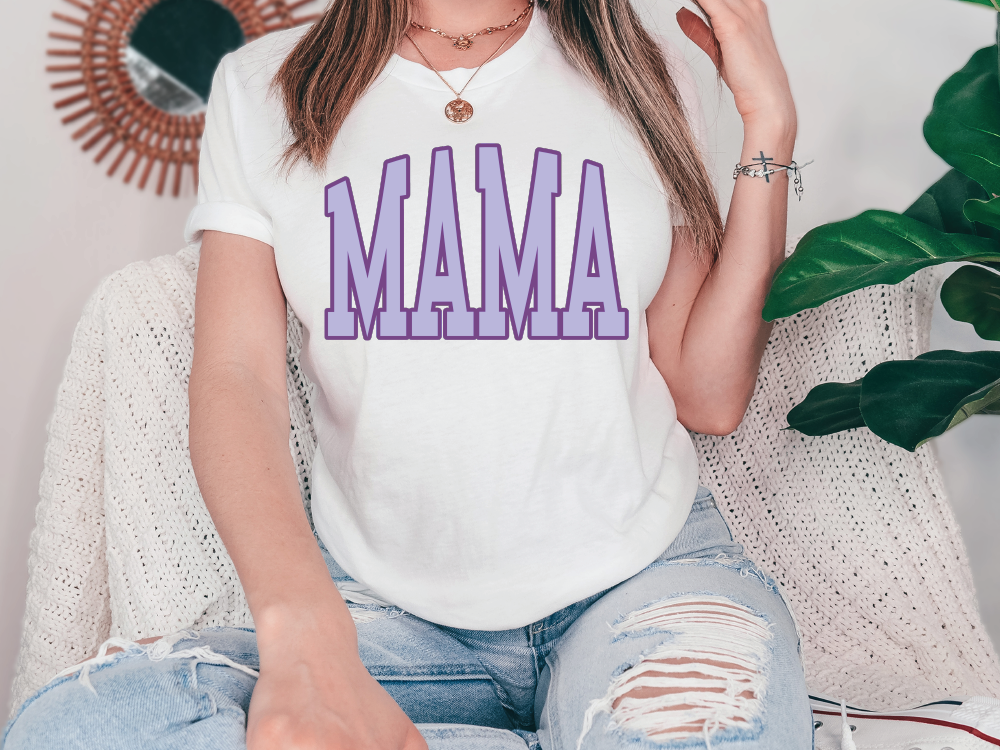 a woman sitting on a couch wearing a white shirt with the word mama printed on