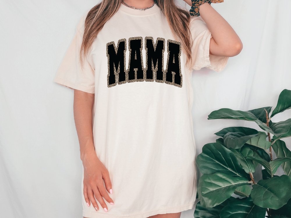 a woman wearing a white shirt with the word mama printed on it