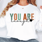 a woman wearing a sweatshirt that says you are enough