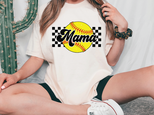 a woman sitting on the ground wearing a tee shirt with a softball on it