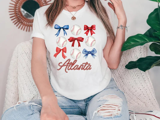 a woman sitting on a couch wearing a white shirt with red, white and blue