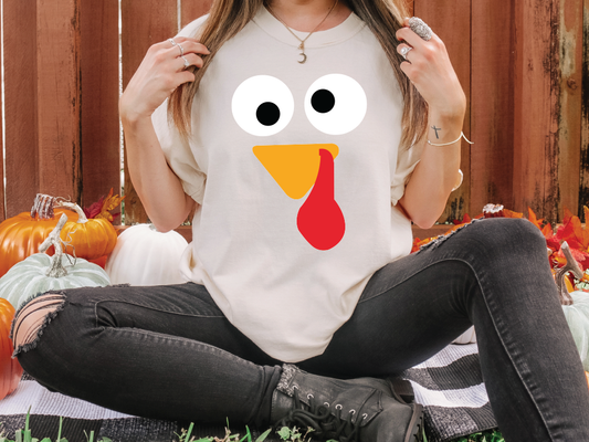 a woman sitting on the ground with a turkey shirt on