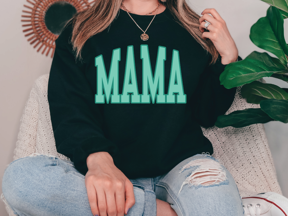 a woman sitting on a couch wearing a black sweatshirt with the word mama printed on