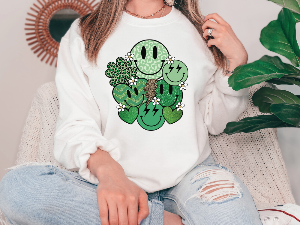 a woman sitting on a couch wearing a white sweatshirt with a shamrock face on it