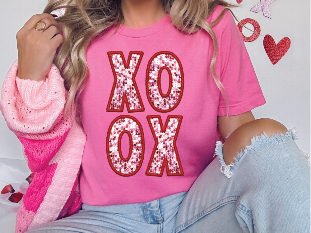 a woman wearing a pink shirt with the word xo on it
