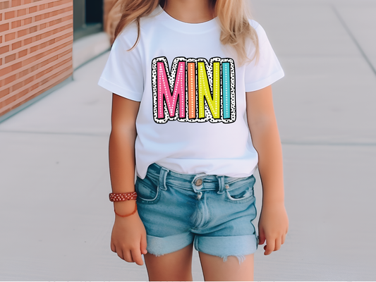 a little girl wearing a white shirt with the word mnn on it