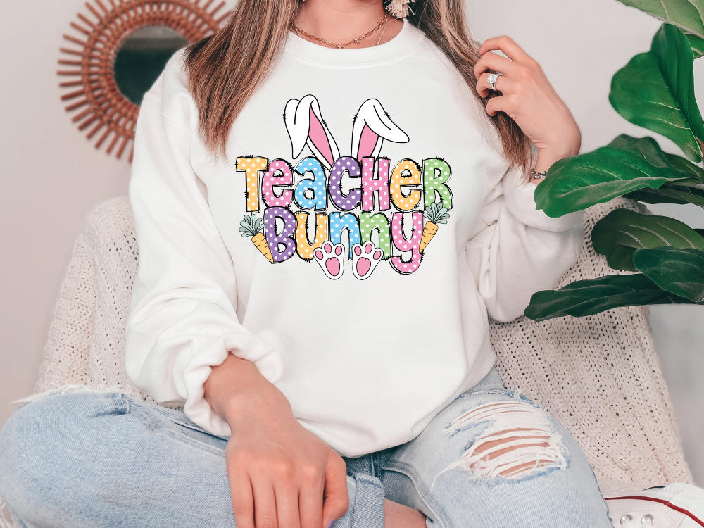a woman sitting on a couch wearing a teacher bunny sweatshirt