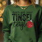 a woman wearing a green sweatshirt that says don't get your tinsel in