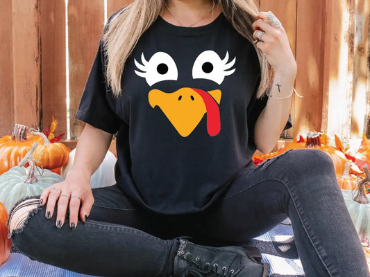 a woman sitting on the ground with a turkey on her shirt