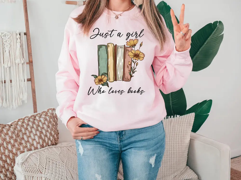 a woman wearing a pink sweatshirt that says just a girl who loves books