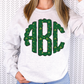 a woman wearing a white sweatshirt with a green monogrammed turtle on it