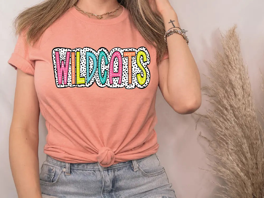 a woman wearing a pink shirt with the word wildcats on it