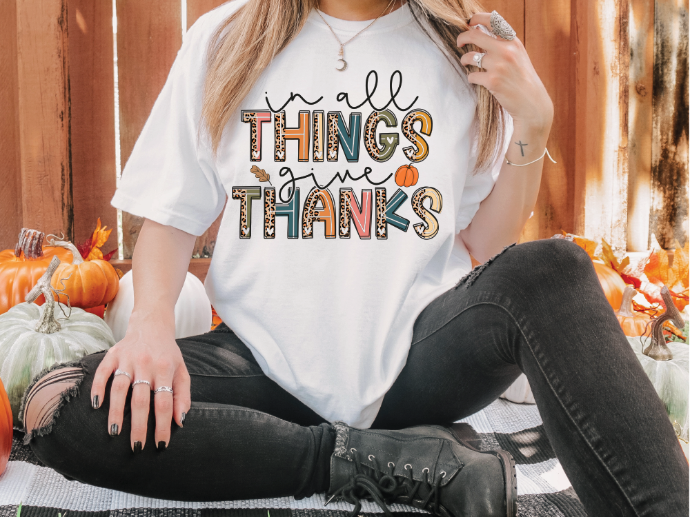 a woman sitting on the ground wearing a t - shirt that says, all things