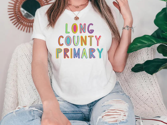 a woman sitting on a couch wearing a long county primary t - shirt